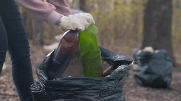 Mulher colocando garrafas de plástico em um saco — Vídeo de Stock