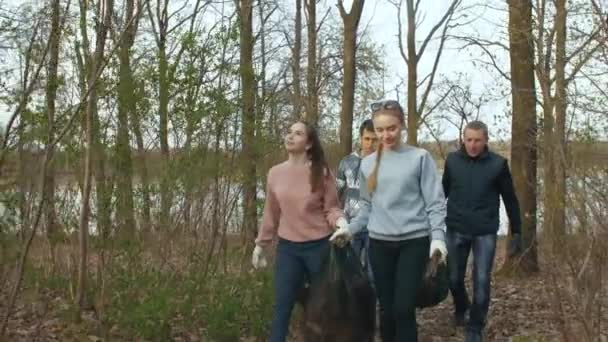 Волонтеры с мешками для мусора прогуливаются по парку — стоковое видео