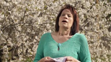 Çiçek açan ağacın yanında hapşıran kadın