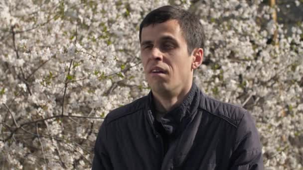 Férfi tüsszentés közelében virágzó fa — Stock videók