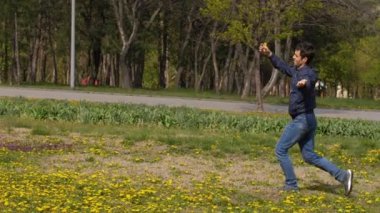 Gülünç, mutlu bir adam elinde çiçekle çayırlarda koşuyor.