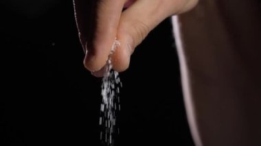 Parmaklar siyah arkaplandaki yemeği tuzlar.