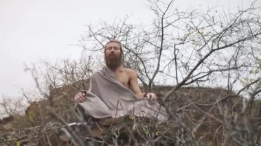 Kayanın üzerinde meditasyonda oturan sofu yogi.