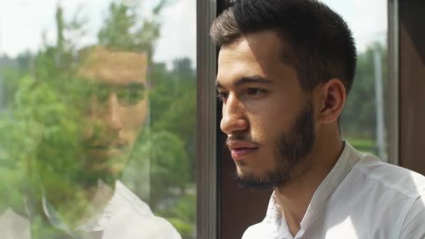 Junger Mann spiegelt sich in einem Fenster — Stockvideo