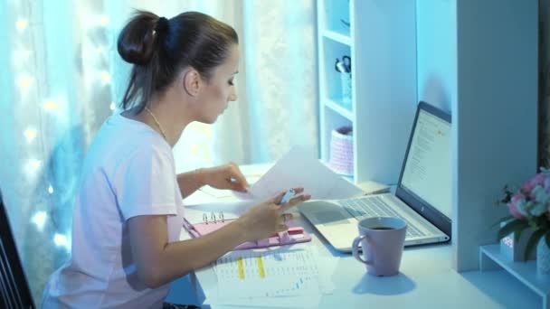 Mulher trabalhando com papéis e laptop à noite — Vídeo de Stock