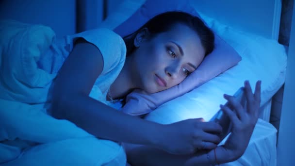 Dépendance au smartphone. Femme dans les médias sociaux dans un lit — Video