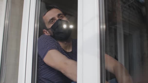 Hombre con mascarilla detrás de la ventana — Vídeo de stock