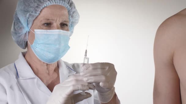 Dokter vaccineert een man in de kliniek — Stockvideo