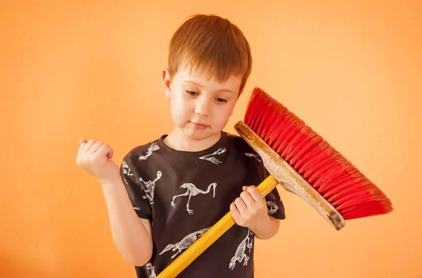 Criança muito caucasiana com uma vassoura, casa tarefas imagem stock . — Fotografia de Stock