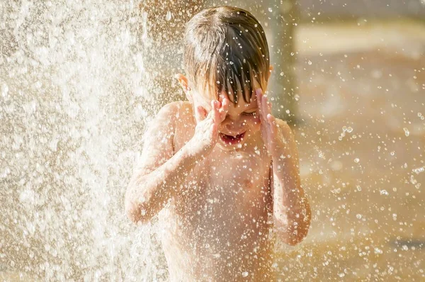 Ευτυχισμένο παιδί απολαμβάνει το παιχνίδι του νερού στη ζέστη του καλοκαιριού. — Φωτογραφία Αρχείου