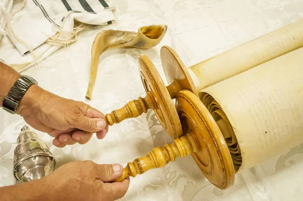 Hands of a Caucasian man holding the handles of the Torah scrolls. — Stock Photo, Image