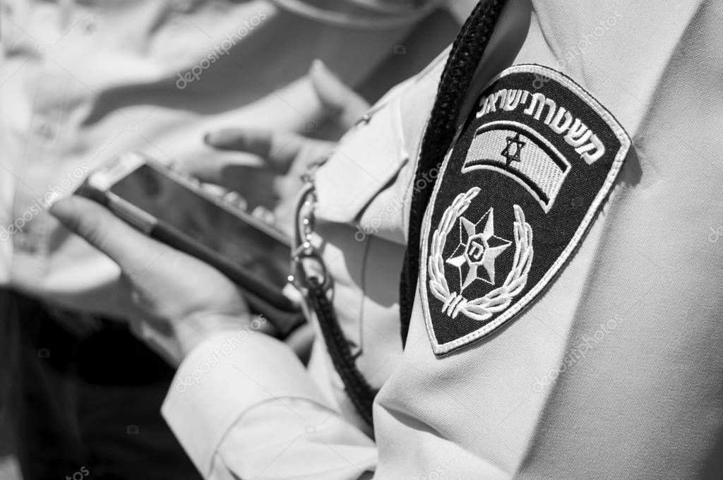 TEL AVIV, ISRAEL. April 9, 2014. Israeli female police officer with an emblem on her uniform holding cellular phone in her hands.