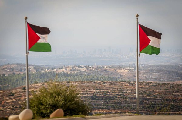 RAWABI, PALESTINIAN AUTHORITY, WEST BANK. November 25, 2017. Tel Aviv (Gush Dan) seen in the horizon through Palestinian flags on the top of the hill in Rawabi.