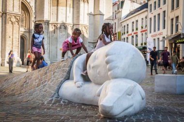 Antwerp, Belçika. 17 Temmuz 2017. Bir çocuk Nello heykeli ve köpeği Patrasche Antwerp Katedrali tarafından oynamaya üç küçük Afrikalı kız. Onlar bir roman 