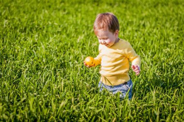 Şirin ve mutlu beyaz erkek bebek yeşil alanda ellerini sarı limon ile.