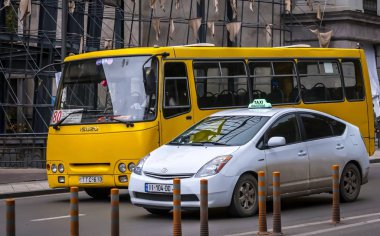 Tiflis, Georgia. 23 Kasım 2019. Tipik sarı bir banliyö otobüsü ve Tiflis şehir merkezinde beyaz bir taksi. Gürcistan 'da toplu taşıma.