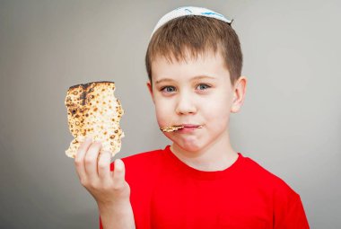 Beyaz kippah şapkalı beyaz beyaz beyaz çocuk shmura matzo yiyor. Pessakh için mayasız bir parça geleneksel Yahudi ekmeği. Yahudi bayramı..