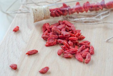 Goji meyveleri bir ahşap tahta üzerinde bir cam kap içinde