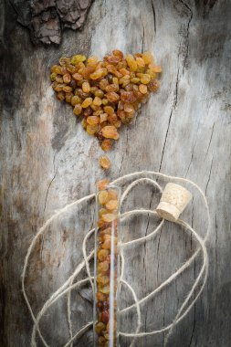 Raisins in a glass flask on aged wood. clipart