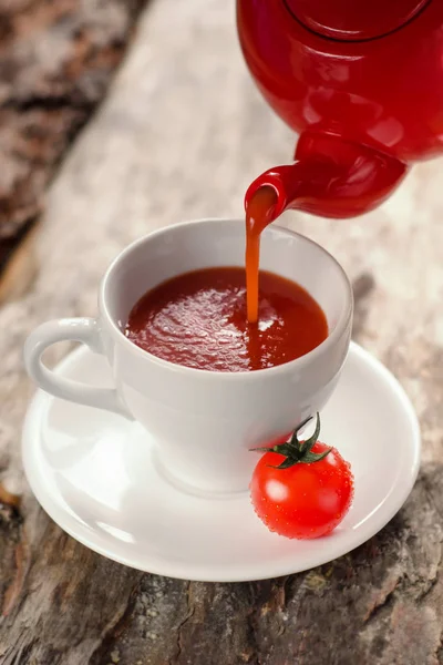 Chaleira vermelha está derramando suco de tomate em uma taça branca — Fotografia de Stock