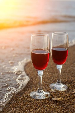 Batan güneşin önünde iki kırmızı şarap kadehi..
