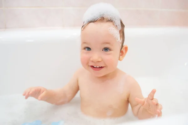 Маленька дівчинка з піною на голові посміхається у ванній. Мила дівчинка щаслива у ванній. Чарівний дитячий портрет. Догляд за шкірою. Охорона здоров'я. Щаслива сім'я — стокове фото