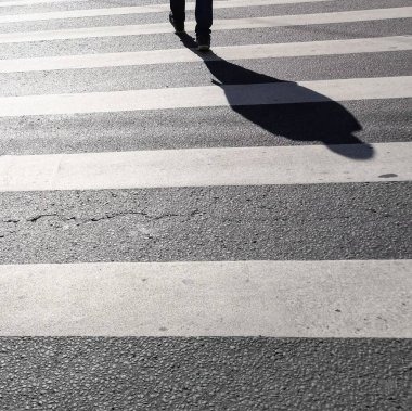 Bacaklı ve gölgeli asfalt zemin zebra yaya geçidinden asfalt yolu geçen vatandaşlar