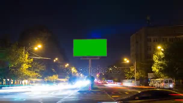 Een bord met een groen scherm op een achtergrond van stadsverkeer met lange blootstelling. Time-lapse. De camera beweegt weg — Stockvideo