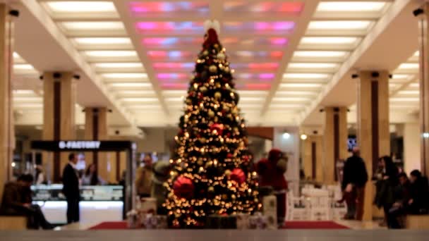 Árvore de Natal desfocada em um centro comercial com pessoas ambulantes — Vídeo de Stock