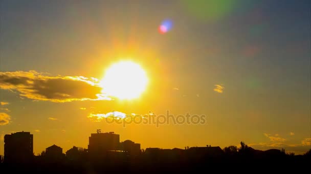 Precioso Time Lapse de puesta de sol, con gran sol dorado, con nubes doradas, con destellos de lente, sobre el fondo de la silueta de la ciudad. El enfoque de la cámara . — Vídeo de stock