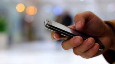 A el kullanır siyah smartphone insanlar ve bokeh ışıklar yürüyüş arka plan üzerinde mans