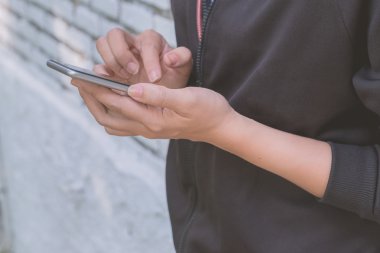 Kızı sokakta smartphone ile kapatın. Vintage filtre
