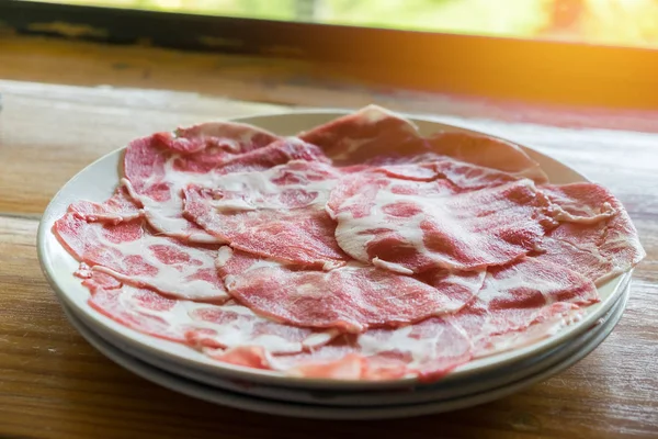 Deslize a carne crua no prato na mesa de madeira — Fotografia de Stock