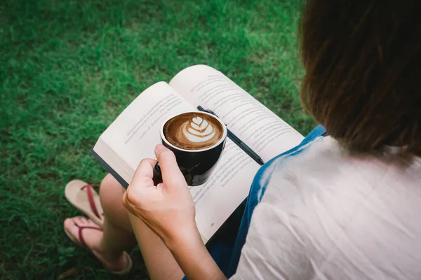 Cute lovely young woman reading book and drinking coffee at outd — Stock Photo, Image