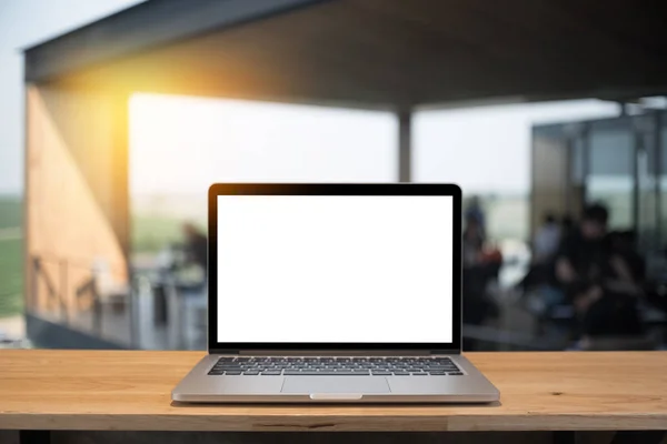 Laptop with blank screen on table of a cafe.