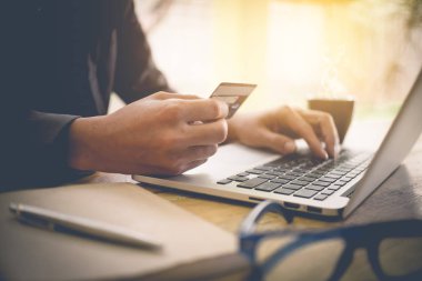 Bir kredi kartı tutan ve lapto kullanarak online ödeme, adam'ın eller