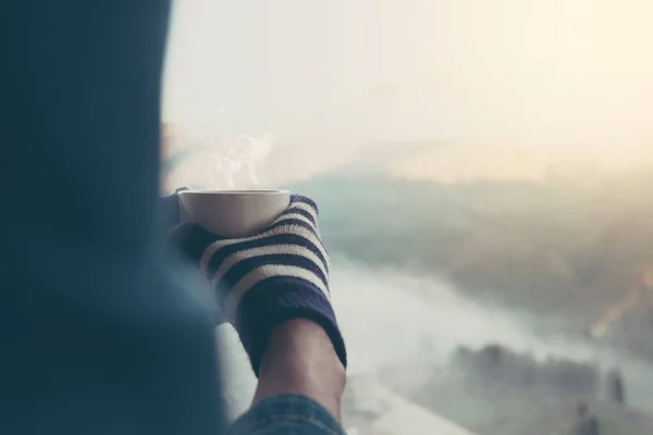 Mãos segurando xícara quente de café ou chá na luz solar da manhã com — Fotografia de Stock