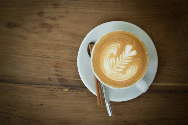 Vista superior de uma caneca de café arte latte sobre fundo de madeira . — Fotografia de Stock