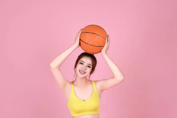 Piękna kobieta azjatyckich, uśmiechając się i trzymając piłkę kosz z różowym — Zdjęcie stockowe