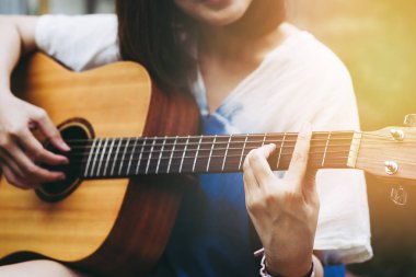 Genç kadın vintage filtre doğurur ile gitar çalmak yakın çekim