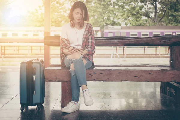 Chica viajero utilizando la tableta con un equipaje sentado y esperando fo — Foto de Stock