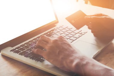 Kredi kartı tutan ve dizüstü bilgisayar kullanan eller. Çevrimiçi alışveriş