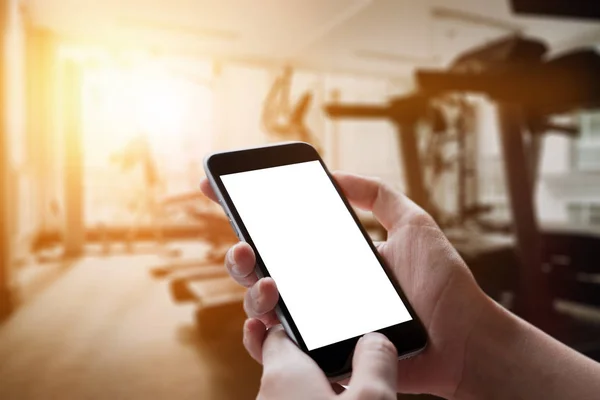 Akıllı telefon aygıtının boş ekran spor salonunda tutan bir adam el.