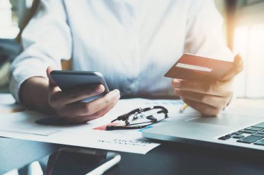 Kredi kartı tutan ve online alışveriş için akıllı telefon kullanan genç bir kadın. Çevrimiçi ödeme alışveriş kavramı