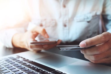 Online ödeme, kredi kartı tutan ve online alışveriş için akıllı telefon kullanarak adamın elleri.