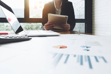 Ofiste oturan ve çözümleme yatırım iş belge kar veya ciro grafiği grafik üzerinde çalışma alanı tablosu, iş fintech kavramı analiz etmek için tablet ve dizüstü bilgisayar kullanarak iş kadını