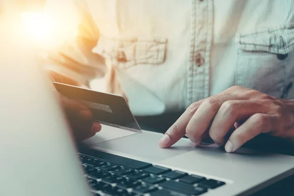 Pago en línea, manos del hombre sosteniendo la tarjeta de crédito y el uso de ordenador portátil para compras en línea . — Foto de Stock