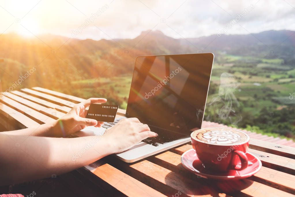Work life balance. Business man using laptop computer and credit card for online financial with a cup of coffee and beautiful mountain view background.