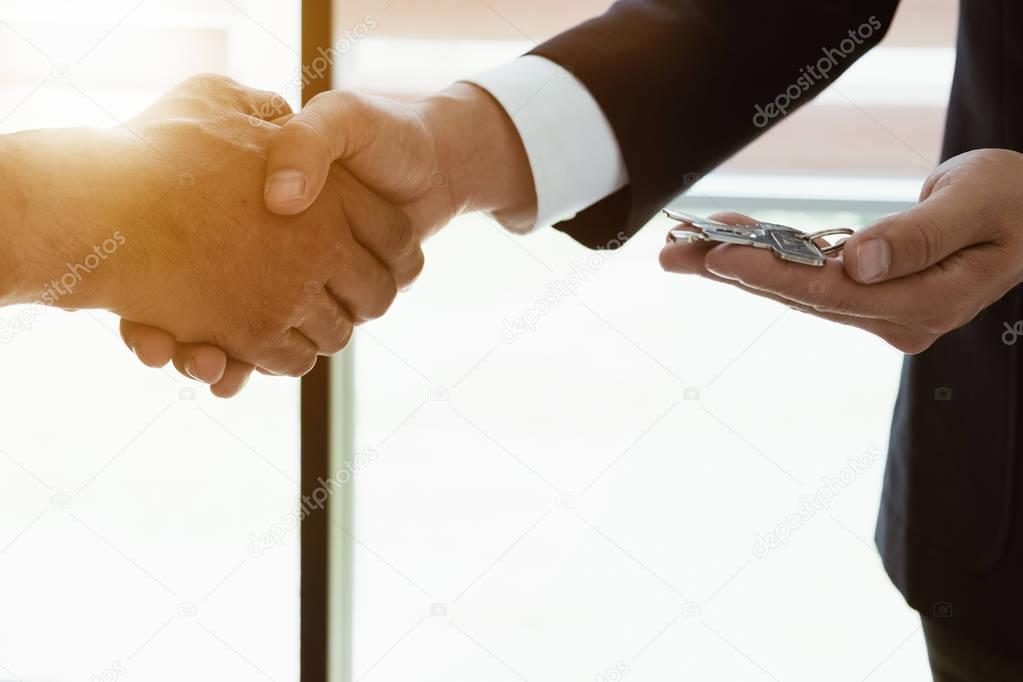 Image of side view, Real estate broker agent and customer shaking hands and give keys after signing contract documents for realty purchase, Bank employees congratulate, Concept mortgage loan approval.
