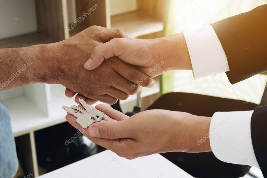 Image of above view, Real estate broker agent and customer shaking hands and give keys after signing contract documents for realty purchase, Bank employees congratulate, Concept mortgage loan approval.